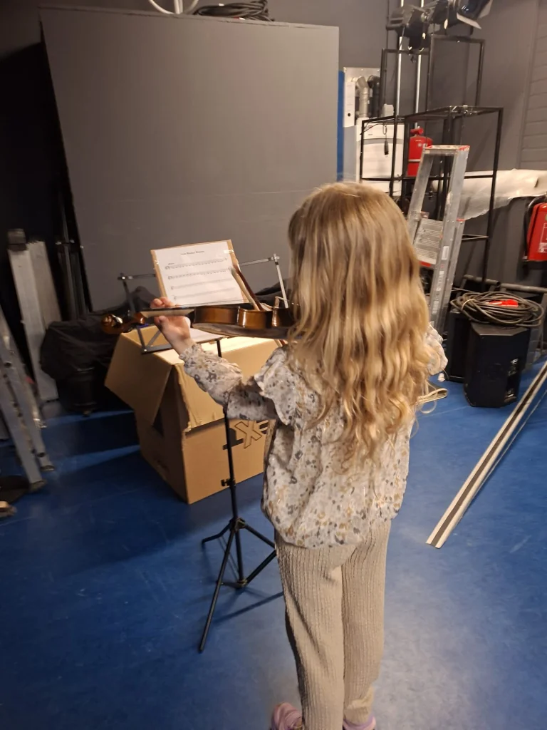 A student playing the violin at a music stand